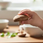 A close-up, softly lit photograph showcasing a child's hand gently holding a cooked shiitake mushroom, illustrating the safety of shiitake mushroom for kids.