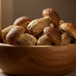 A rustic wooden bowl filled with high-quality, whole dried porcini mushrooms sits on a textured linen cloth.