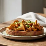 A beautifully plated chanterelle mushroom toast recipe showcases golden sauteed chanterelles atop crispy artisanal toast, garnished with fresh herbs.