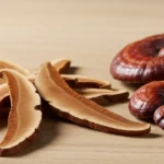 An editorial photograph features dried reishi mushroom slices and whole caps neatly arranged on a natural wooden surface, illustrating the traditional use of reishi mushroom for anxiety.