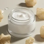 A sleek, minimalist jar of tremella mushroom cream is artfully arranged on a smooth, light-colored stone, surrounded by delicate, translucent tremella mushrooms and subtle hints of dewy green leaves, emphasizing natural skincare and deep hydration.